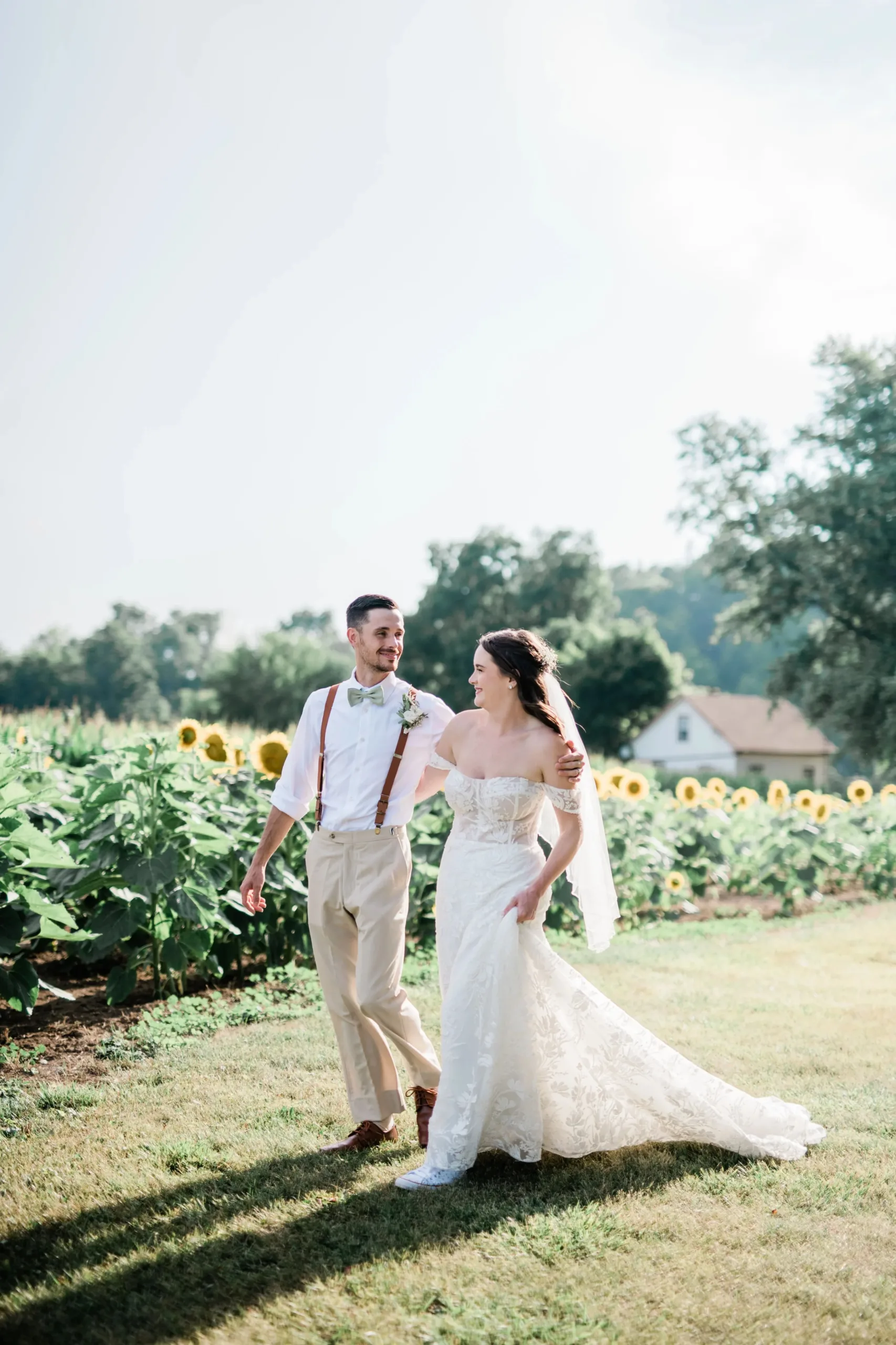 bride and groom walking next to sunflowers