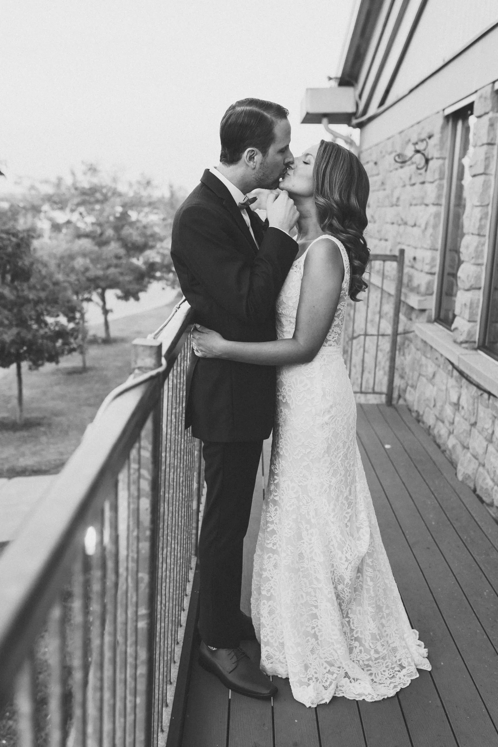 bride and groom kissing on balcony at the lakeview